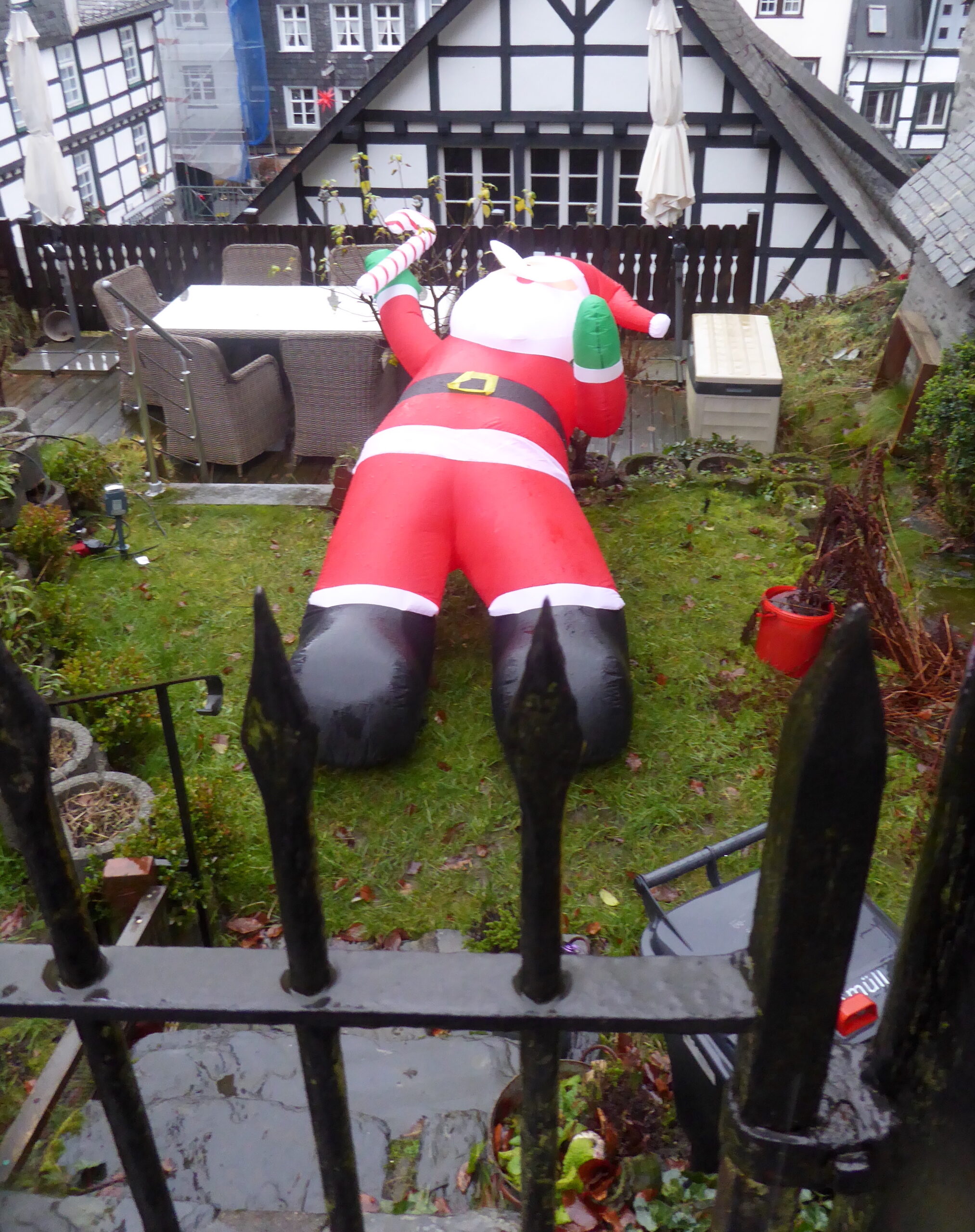 foto van opblaas-kerstmanfiguur omgevallend door de wind en liggend in het gras